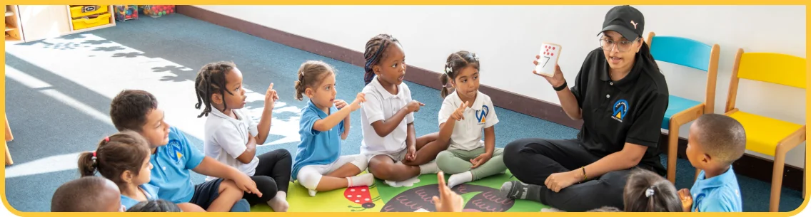 An educator leading a group activity with children seated on the mat